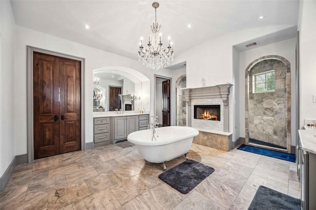 bathroom featuring vanity, a high end fireplace, plus walk in shower, and an inviting chandelier