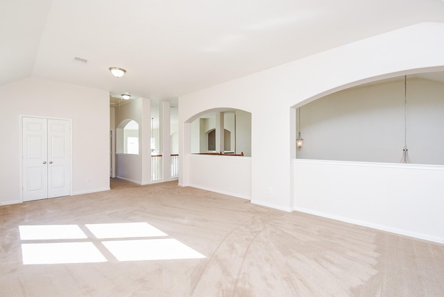 carpeted empty room with vaulted ceiling