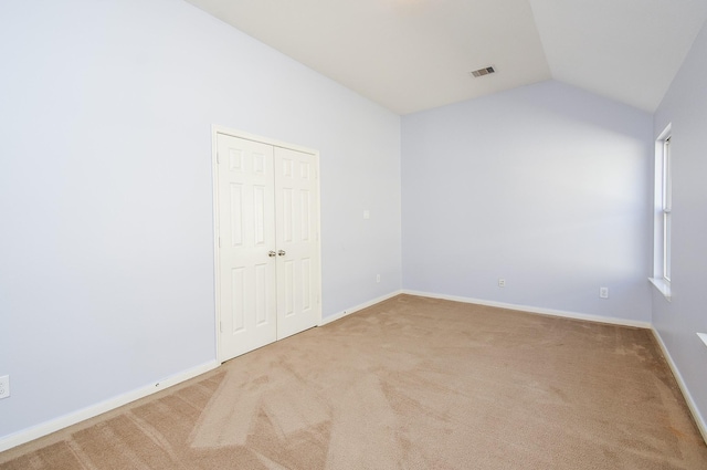 carpeted empty room featuring lofted ceiling