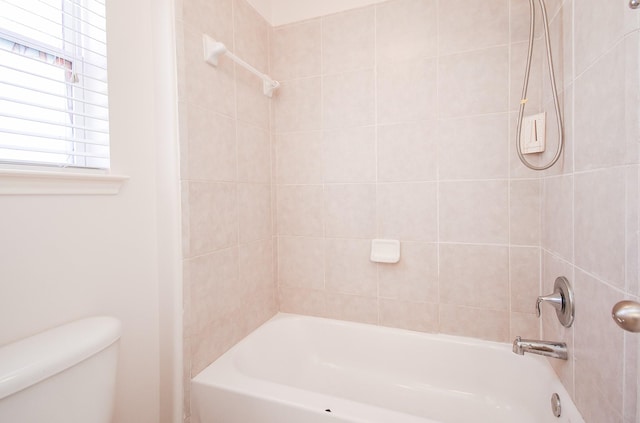 bathroom featuring toilet and tiled shower / bath combo