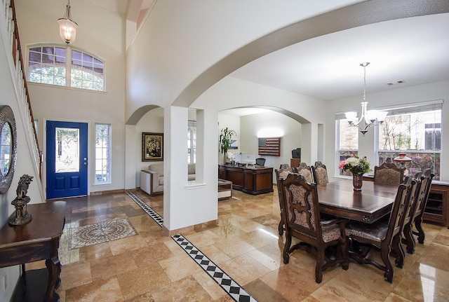 foyer entrance with a towering ceiling, a wealth of natural light, and a chandelier