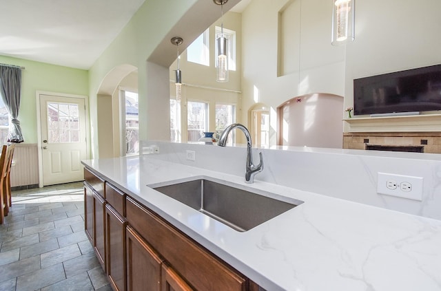 kitchen with pendant lighting, sink, and light stone counters