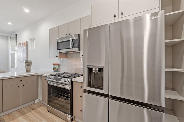 kitchen with stainless steel appliances, light wood-type flooring, and decorative backsplash