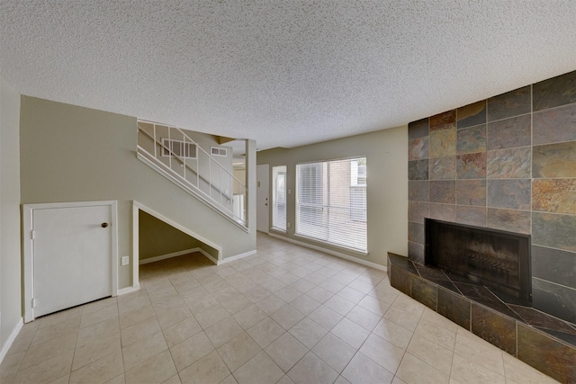 unfurnished living room with a fireplace, a textured ceiling, and light tile patterned floors