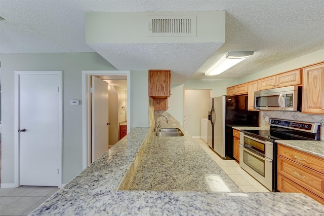 kitchen with sink, light stone counters, light tile patterned floors, stainless steel appliances, and decorative backsplash