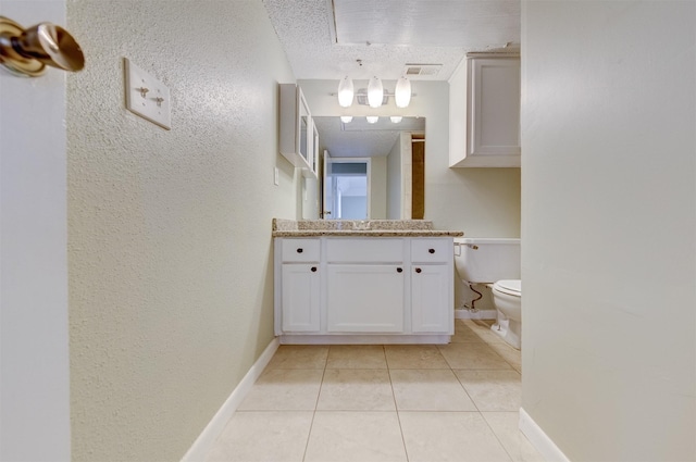 bathroom featuring tile patterned flooring, vanity, a textured ceiling, and toilet