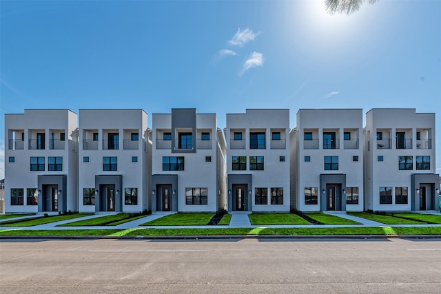 townhome / multi-family property with a front yard and stucco siding