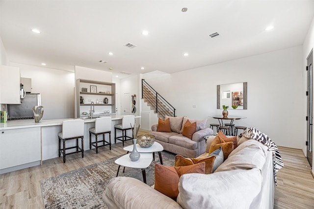 living room featuring light wood-type flooring, visible vents, and recessed lighting