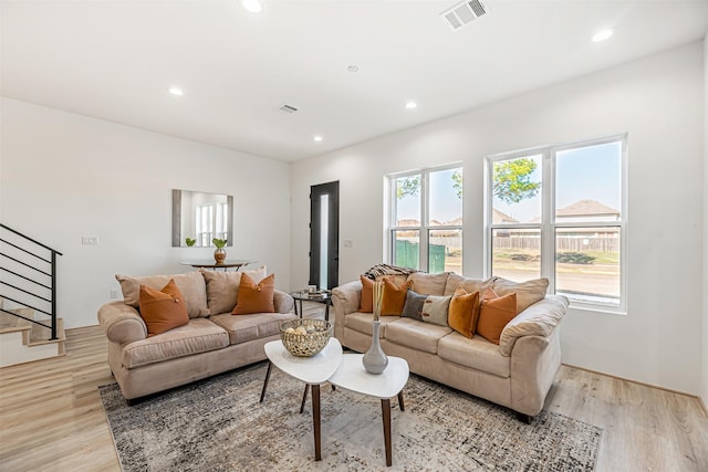 living room with stairway, light wood-type flooring, visible vents, and recessed lighting