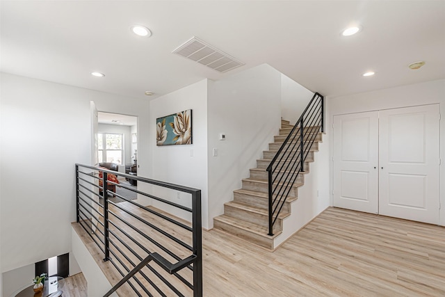 stairway with wood finished floors, visible vents, and recessed lighting