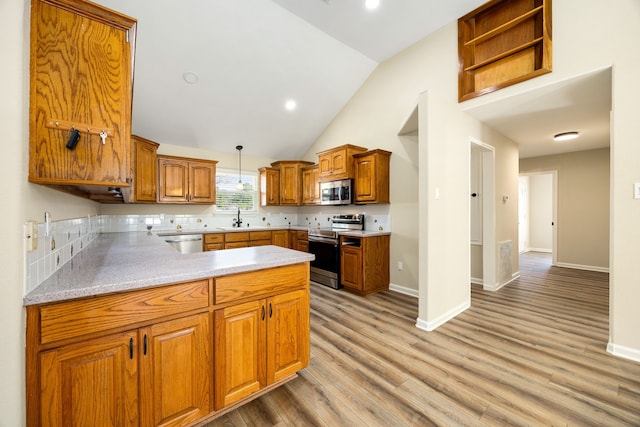 kitchen featuring pendant lighting, sink, appliances with stainless steel finishes, light hardwood / wood-style floors, and kitchen peninsula