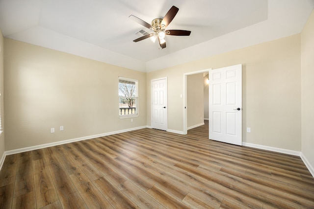 interior space with ceiling fan, a tray ceiling, and dark hardwood / wood-style floors