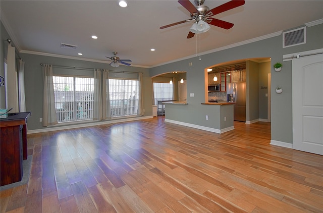 unfurnished living room featuring crown molding, ceiling fan, a barn door, and light wood-type flooring