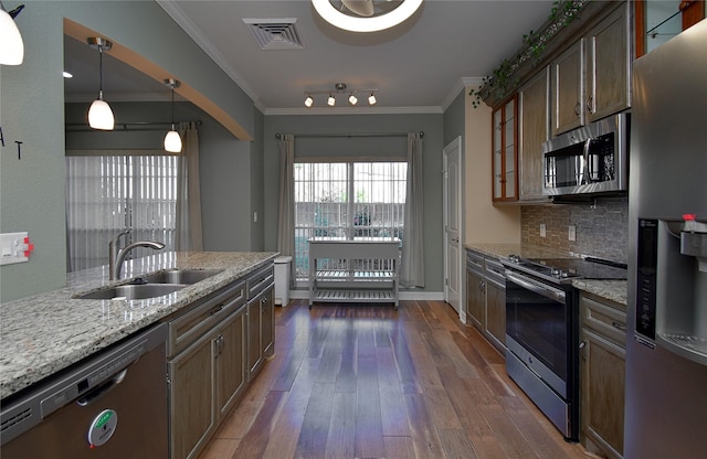 kitchen with pendant lighting, crown molding, stainless steel appliances, light stone counters, and tasteful backsplash