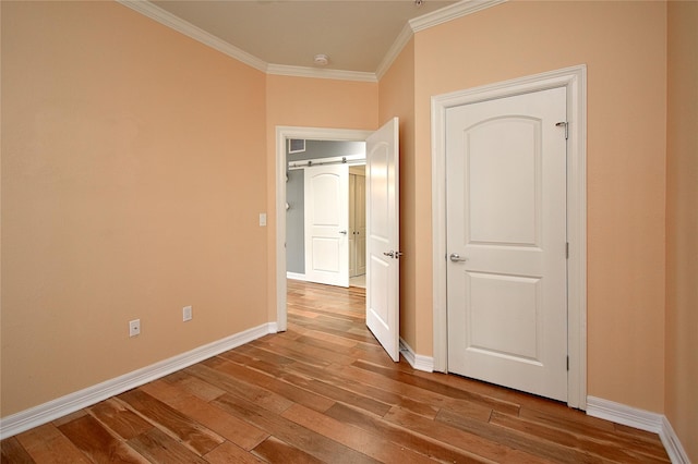 interior space featuring wood-type flooring, ornamental molding, and a barn door