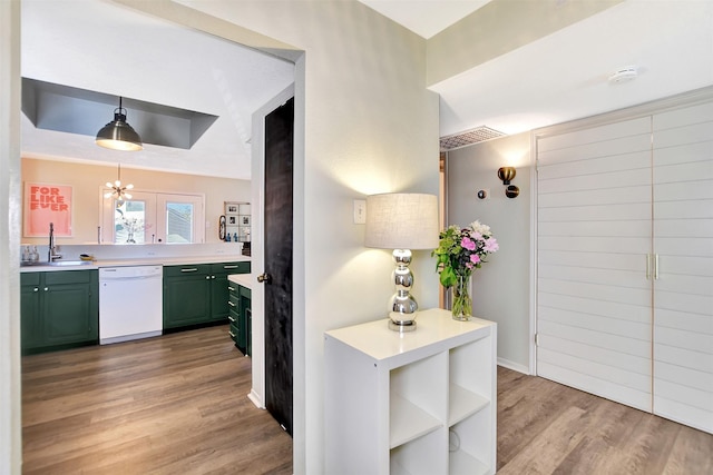 kitchen with pendant lighting, sink, dishwasher, green cabinetry, and light wood-type flooring