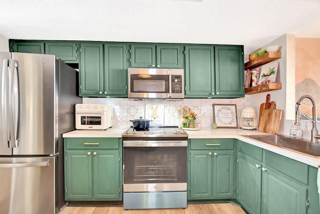 kitchen featuring green cabinetry, appliances with stainless steel finishes, sink, and decorative backsplash