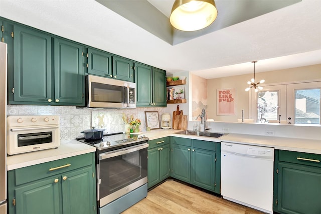 kitchen featuring appliances with stainless steel finishes, pendant lighting, sink, green cabinetry, and light wood-type flooring