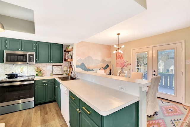 kitchen with appliances with stainless steel finishes, sink, kitchen peninsula, and green cabinets