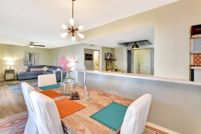 dining area with hardwood / wood-style flooring and ceiling fan with notable chandelier