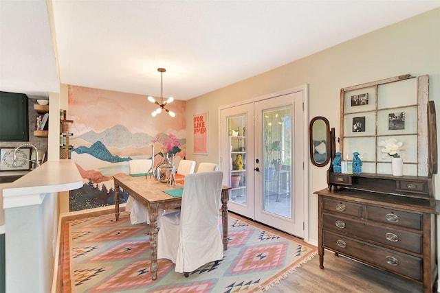 dining space featuring sink, light hardwood / wood-style floors, french doors, and a chandelier