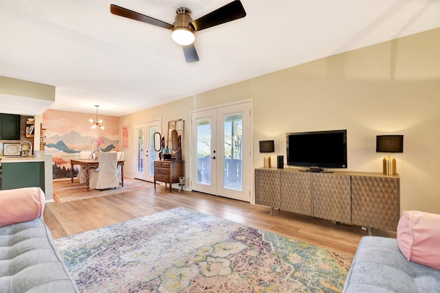 living room with french doors, sink, ceiling fan with notable chandelier, and light hardwood / wood-style floors