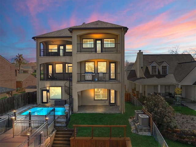 back of house featuring a fenced in pool, stucco siding, a patio area, a balcony, and a fenced backyard