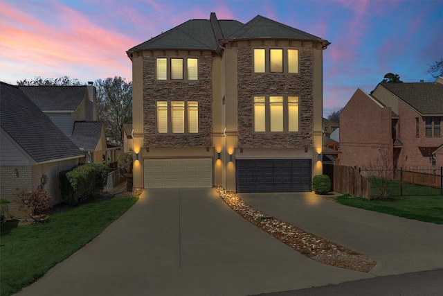 view of front facade with a garage, concrete driveway, stone siding, fence, and stucco siding