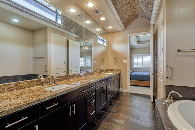 full bath with tiled bath, a sink, visible vents, and baseboards