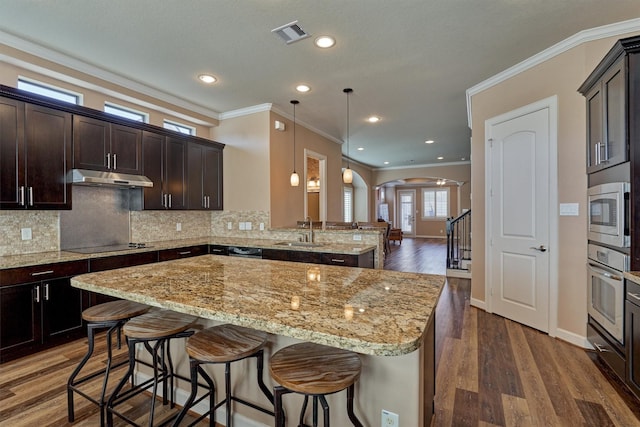 kitchen with arched walkways, visible vents, appliances with stainless steel finishes, a sink, and under cabinet range hood