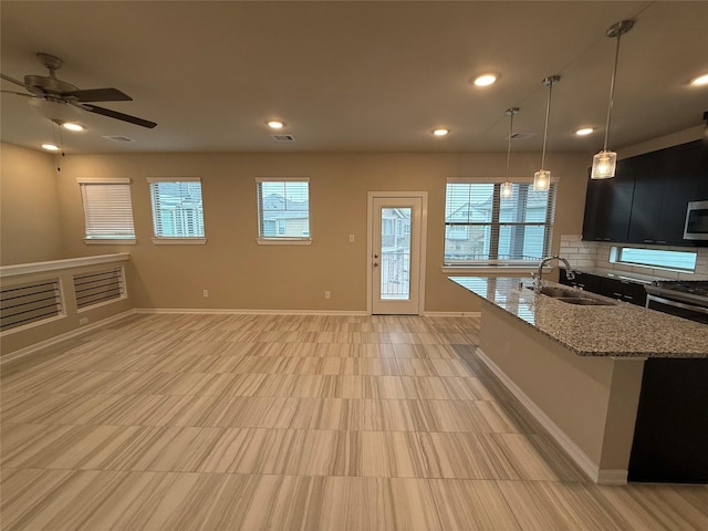 kitchen featuring pendant lighting, sink, appliances with stainless steel finishes, light stone counters, and decorative backsplash