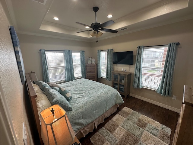 bedroom with ornamental molding, ceiling fan, dark hardwood / wood-style flooring, and a tray ceiling