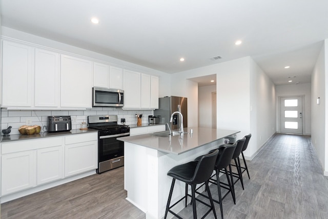 kitchen with a kitchen island with sink, sink, stainless steel appliances, and white cabinets