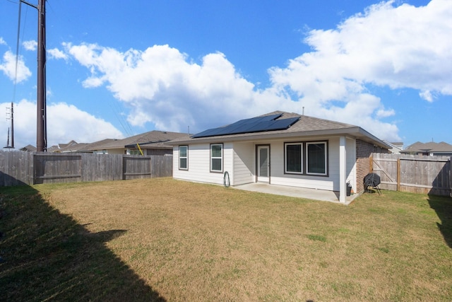 rear view of house with a yard, a patio, and solar panels