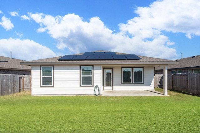 rear view of house with a yard, a patio area, and solar panels