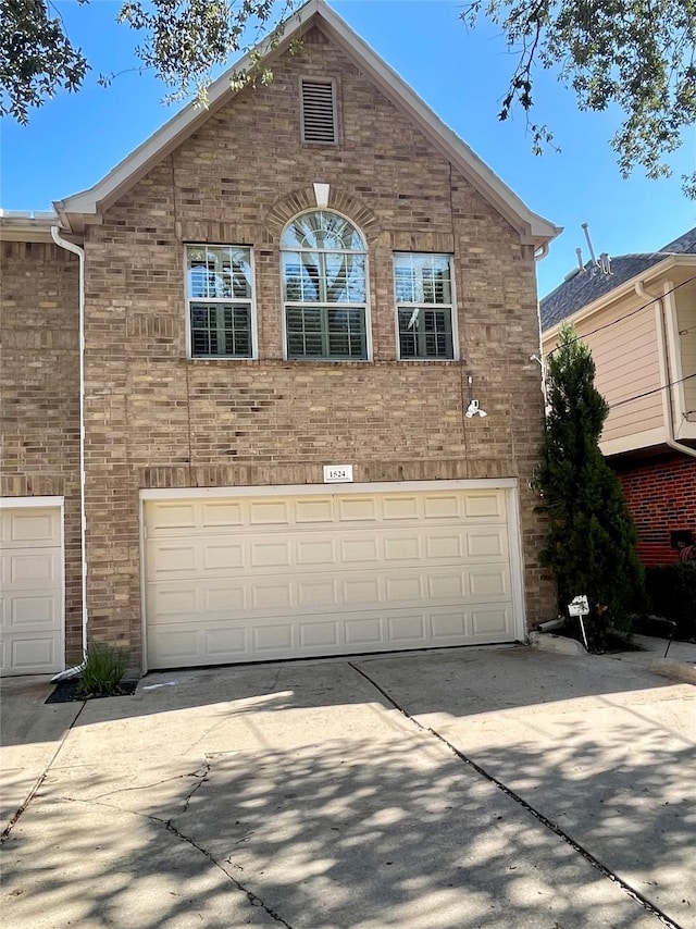 view of front of house with a garage, concrete driveway, and brick siding