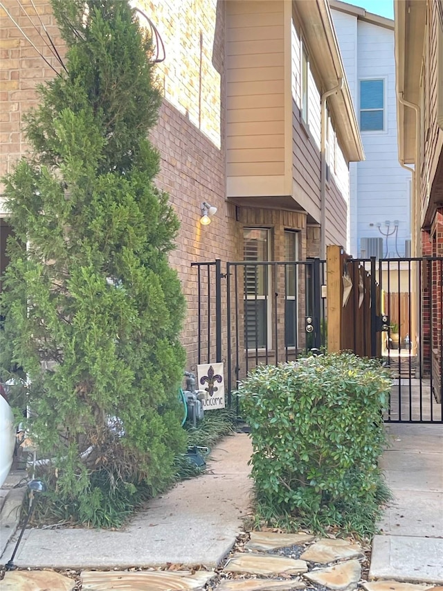 entrance to property featuring a gate, brick siding, and fence