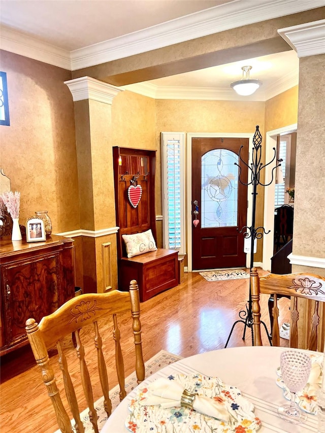 foyer entrance featuring ornate columns, ornamental molding, and wood finished floors