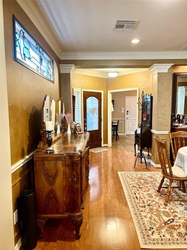 entryway with decorative columns, visible vents, wood finished floors, and ornamental molding