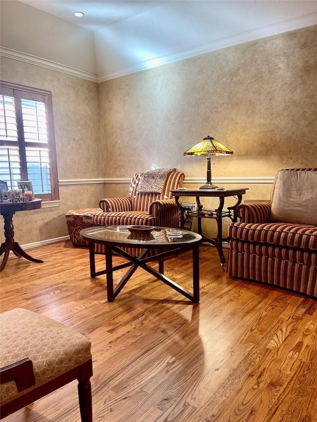 living area with ornamental molding and wood finished floors