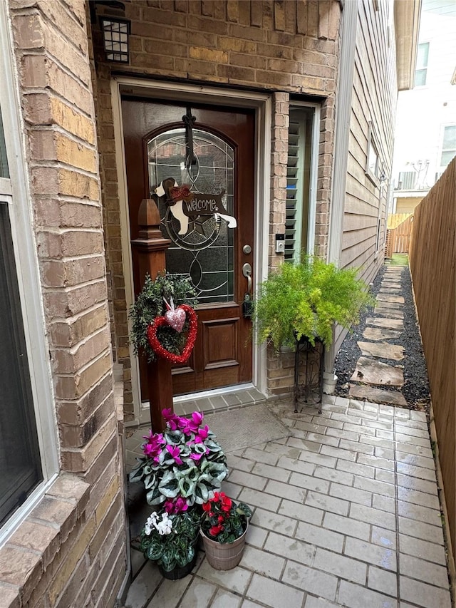 entrance to property with brick siding and fence