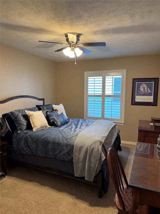 bedroom featuring light carpet, ceiling fan, baseboards, and a textured ceiling