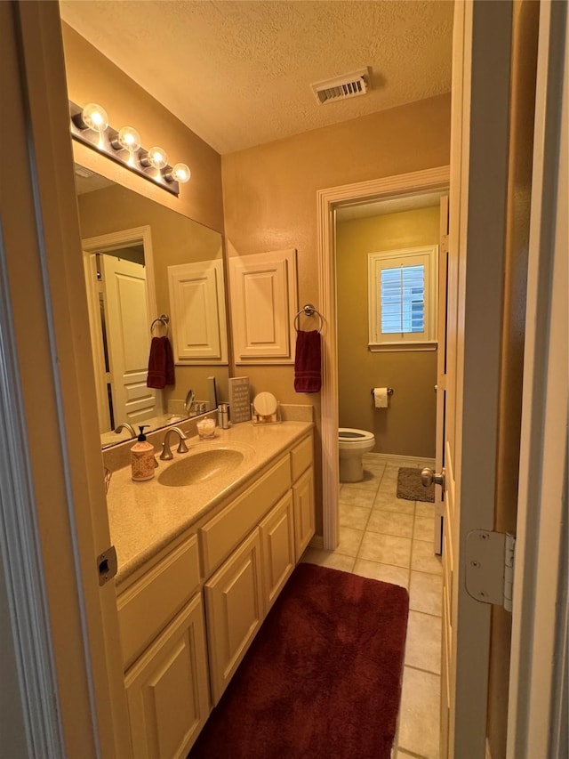 bathroom with visible vents, toilet, tile patterned floors, a textured ceiling, and vanity