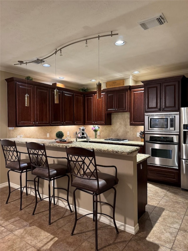 kitchen featuring appliances with stainless steel finishes, backsplash, a breakfast bar, and visible vents