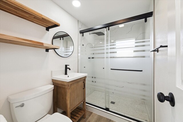 bathroom featuring vanity, wood-type flooring, a shower with door, and toilet