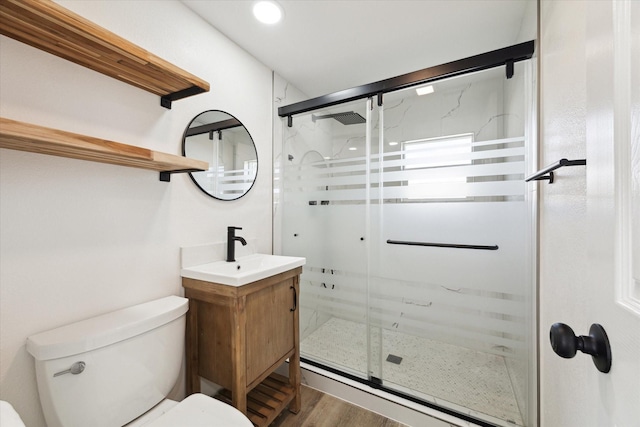 full bathroom featuring toilet, a stall shower, wood finished floors, and vanity