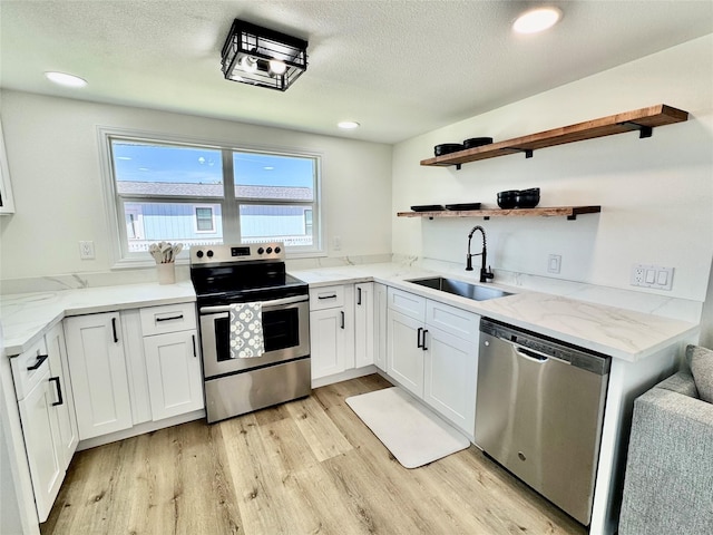 kitchen with stainless steel appliances, light wood-style floors, white cabinetry, open shelves, and a sink