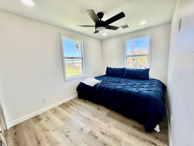 bedroom with baseboards, visible vents, multiple windows, and wood finished floors