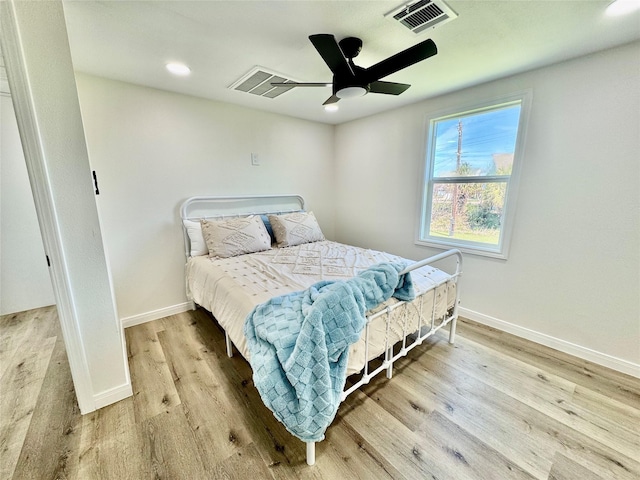 bedroom featuring a ceiling fan, visible vents, baseboards, and wood finished floors