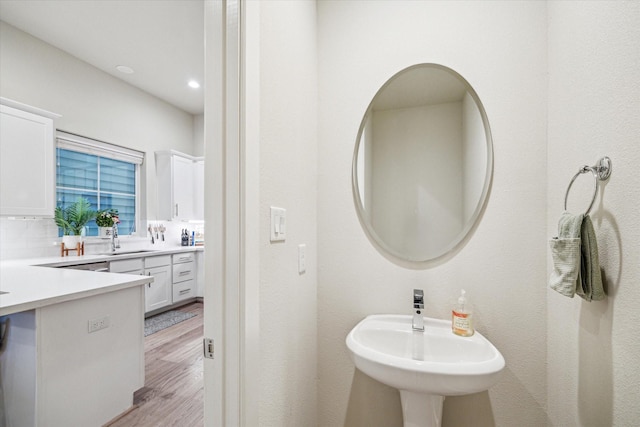 bathroom with sink, hardwood / wood-style floors, and decorative backsplash